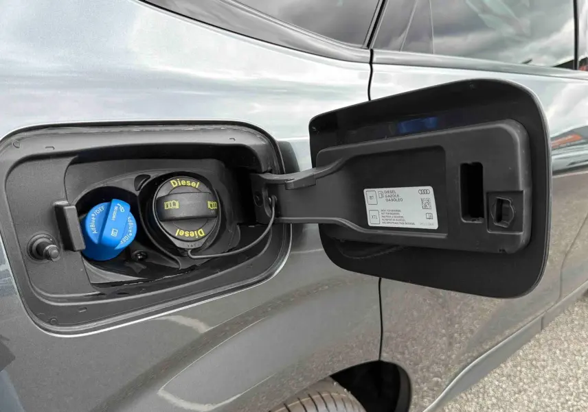 Gros plan sur la trappe à carburant ouverte côté gauche d’un Audi Q3 Sportback gris métallisé.