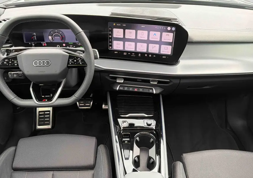 Vue intérieure du tableau de bord et console centrale noire de l'Audi Q3 Sportback avec écran tactile et volant sport multifonctions.