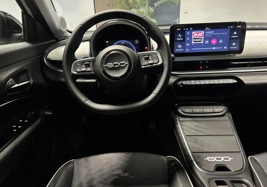 Vue intérieure frontale du tableau de bord et volant noir du Fiat 600 avec écran tactile et console centrale marquée 600.