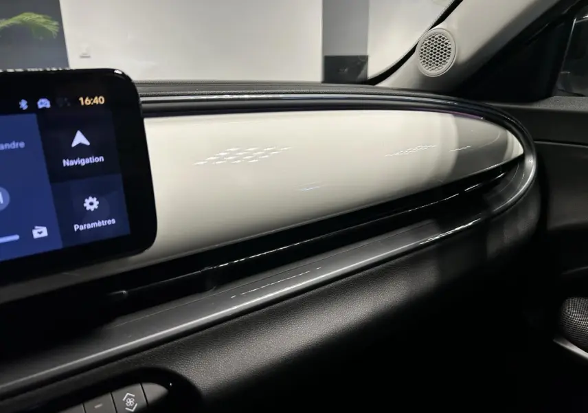 Vue intérieure côté passager du tableau de bord blanc brillant du Fiat 600 1.2 Hybrid avec écran tactile et haut-parleur intégré.