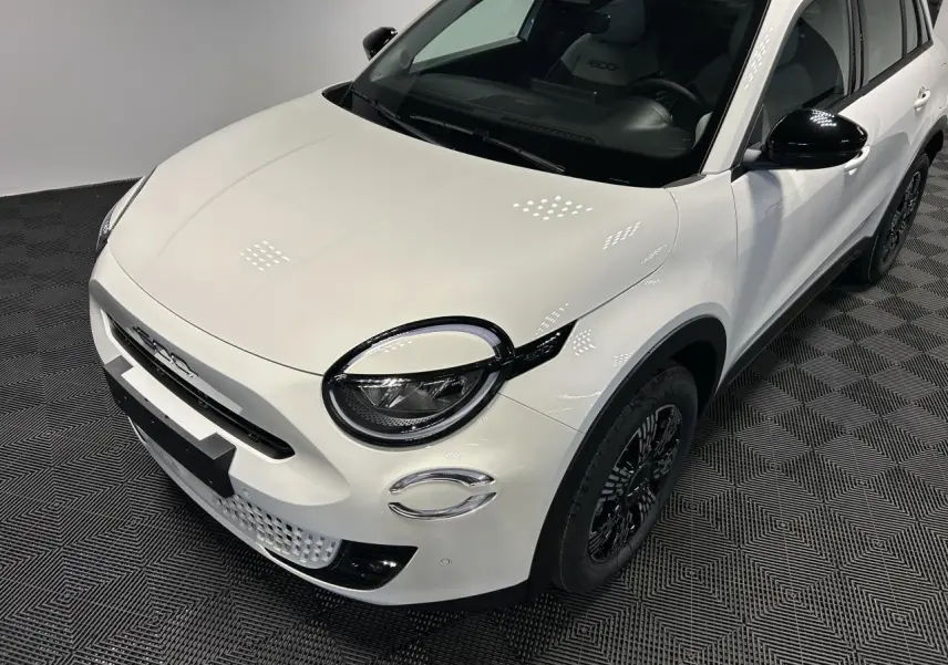 Vue 3/4 avant droit d'une Fiat 600 blanche avec coques de rétroviseurs noires brillantes et jantes alliage noires.