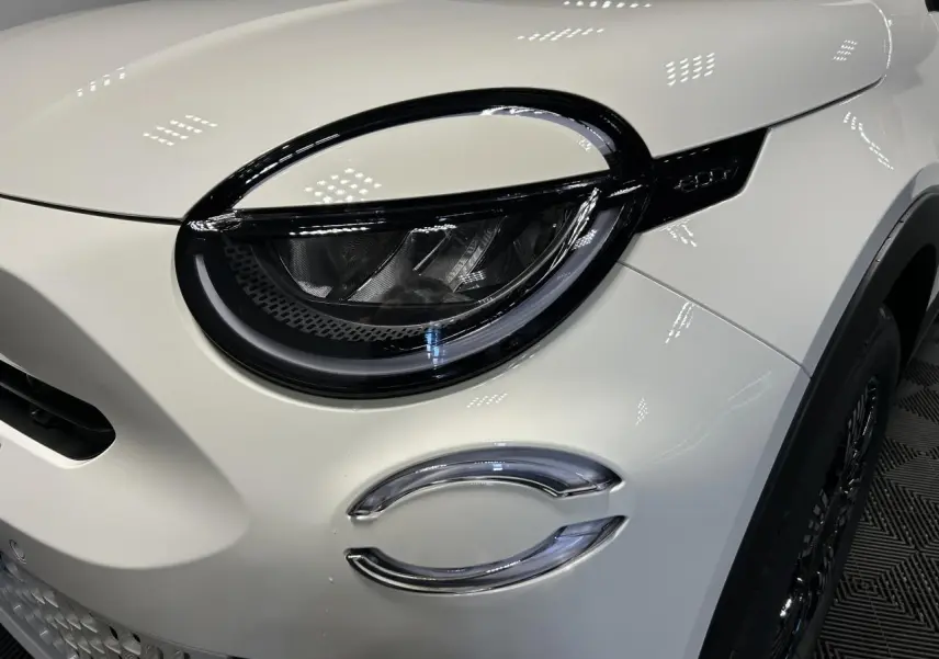 Gros plan sur le phare avant gauche du Fiat 600 blanc avec détails noirs et éclairage LED distinctif.