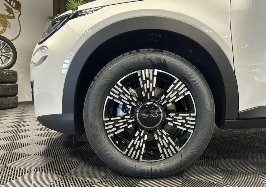 Gros plan sur la roue avant gauche noire et chromée du FIAT 600 blanc avec logo 600 au centre de la jante.
