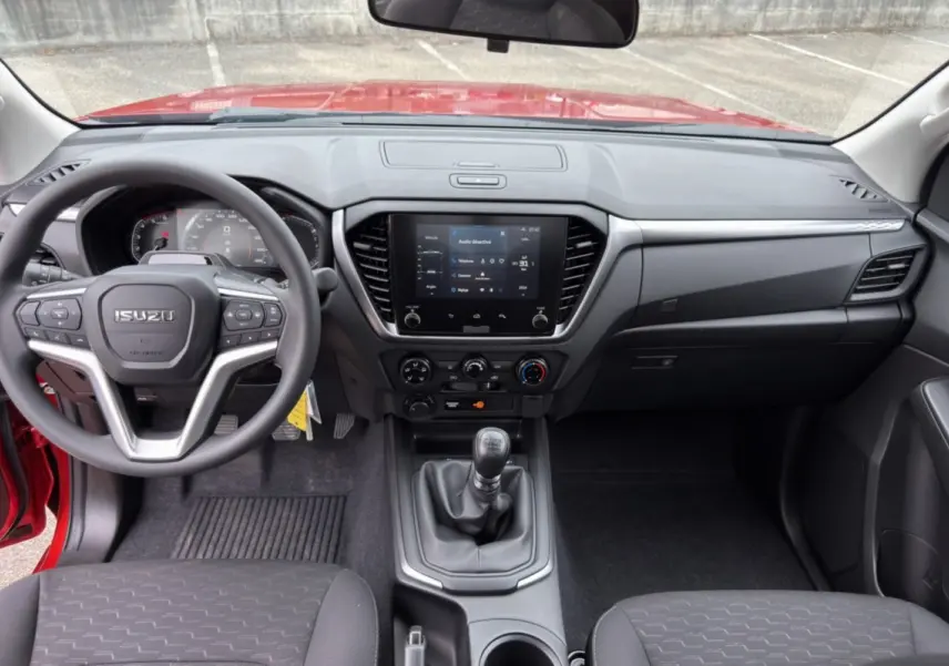Vue intérieure avant de l'Isuzu D-MAX 2026 orange Namibu, volant multifonctions et écran tactile central visible.