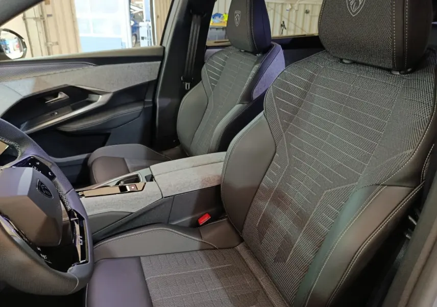 Vue intérieure côté conducteur du Peugeot 5008 1.6 PHEV gris clair, sièges en tissu et cuir avec logo Peugeot brodé sur appuie-tête.