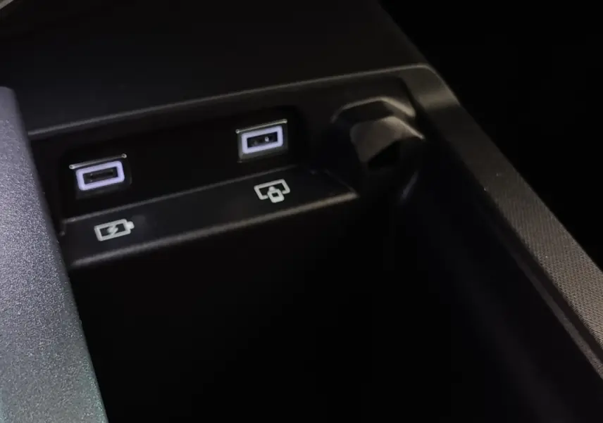 Gros plan sur deux ports USB et une prise 12V dans l'habitacle du Peugeot 5008 gris clair hybride rechargeable.