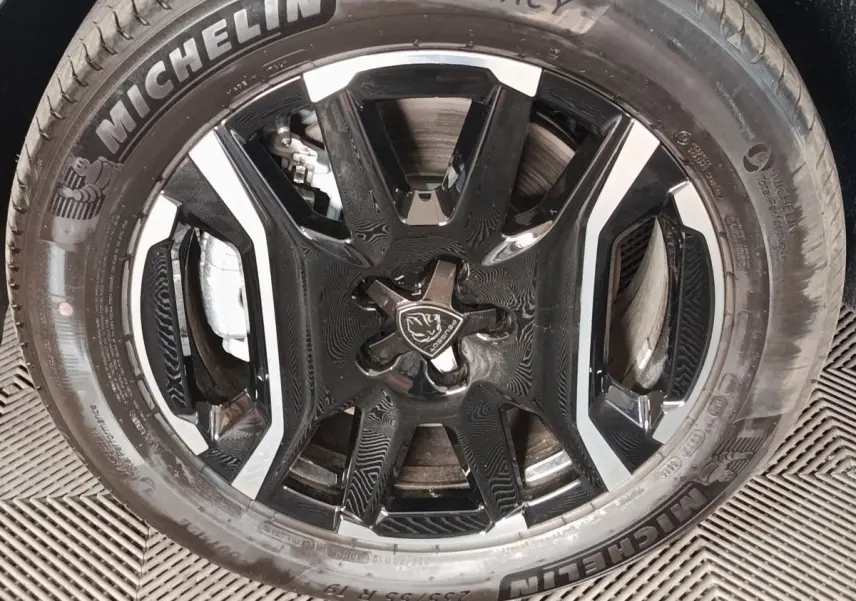 Gros plan sur la roue avant avec jante noire et argentée du Peugeot 5008 1.6 PHEV gris clair de 2026.