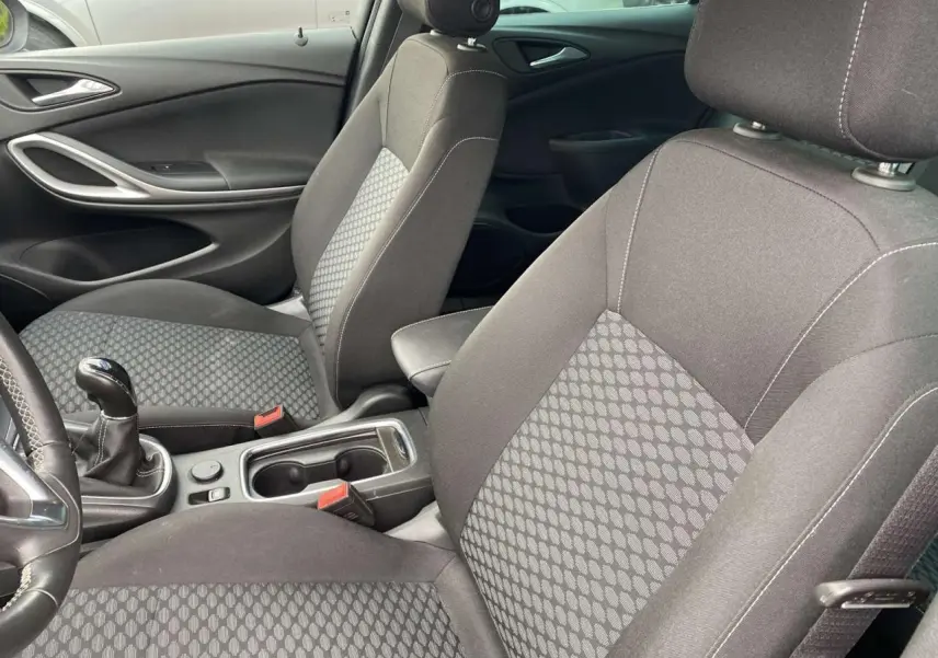 Intérieur avant de l'Opel Astra 2021 avec sièges tissu gris à motifs, levier de vitesse manuel et accoudoir central.