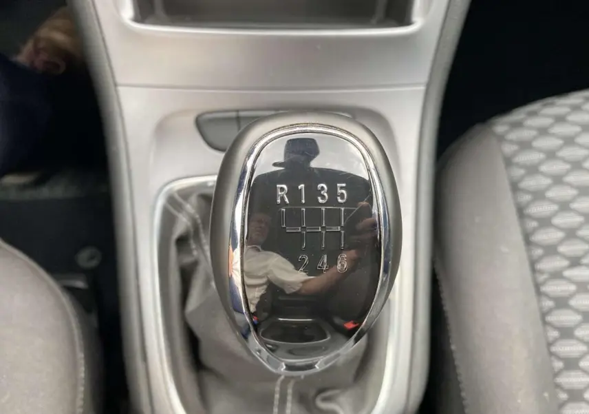 Le levier de vitesses manuel noir brillant de l'Opel Astra 1.2i Turbo Edition, entouré de la console grise.