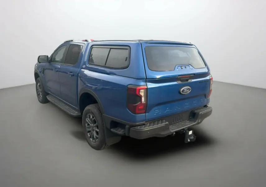 Ford Ranger 3.0 V6 Wildtrak bleu lightning, vue 3/4 arrière droit avec hard-top vitré et attelage.