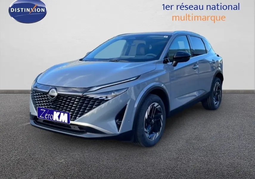 Nissan Qashqai 2025 gris argile métal en 3/4 avant droit, avec calandre noire et jantes bicolores.