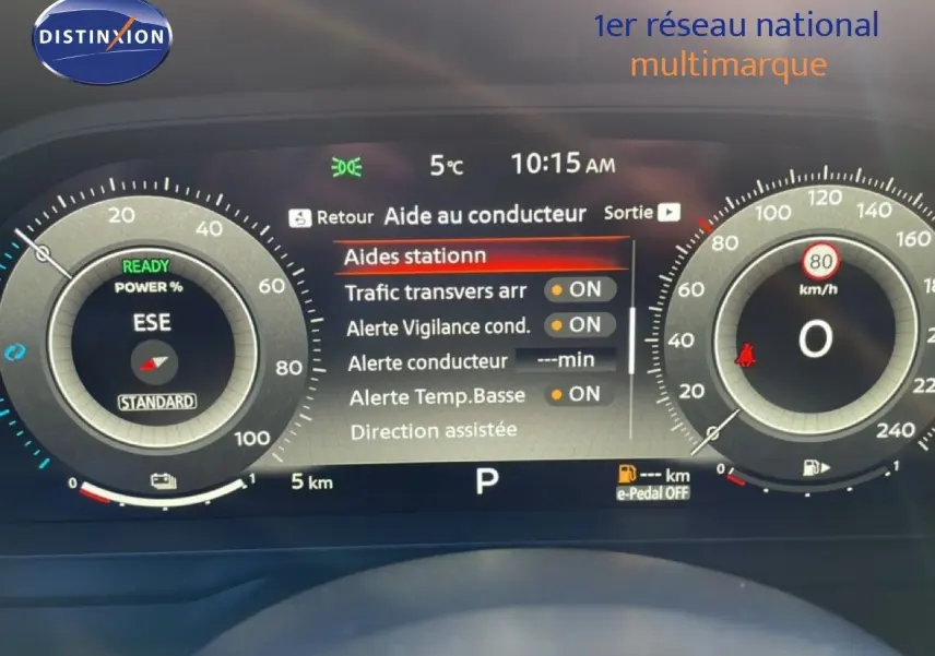 Vue de face du tableau de bord numérique du Nissan Qashqai gris argile, affichant les aides à la conduite et la vitesse à zéro.