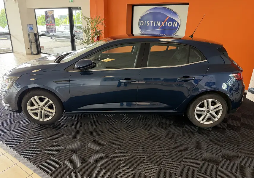 Profil côté gauche d'une Renault Mégane 1.3 TCE 115 Business bleu foncé, 5 portes, en intérieur showroom.