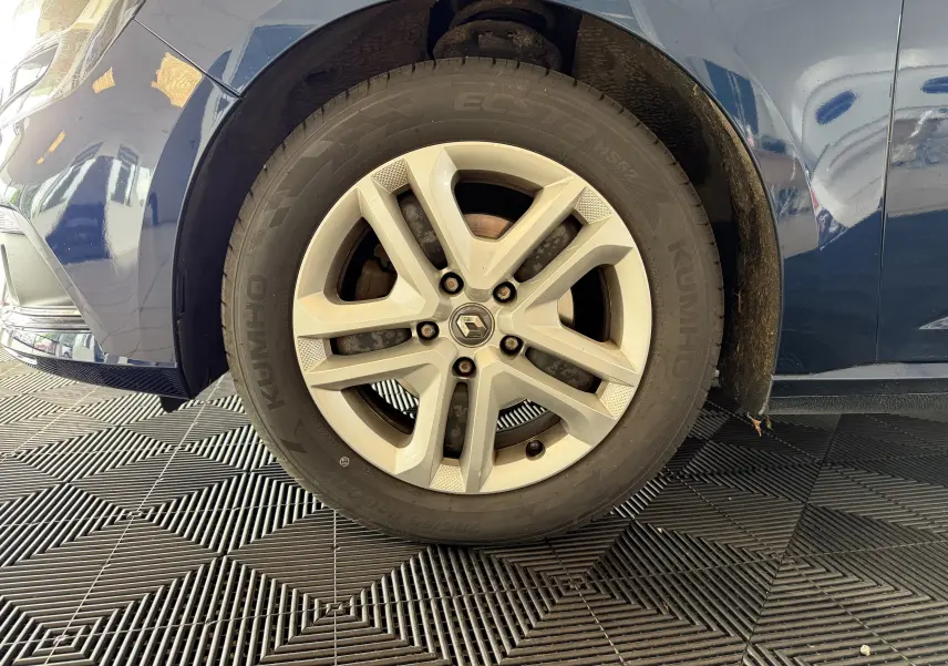 Gros plan sur la roue avant gauche d'une Renault Mégane bleu 2019, mettant en valeur la jante alliage et le pneu Kumho.