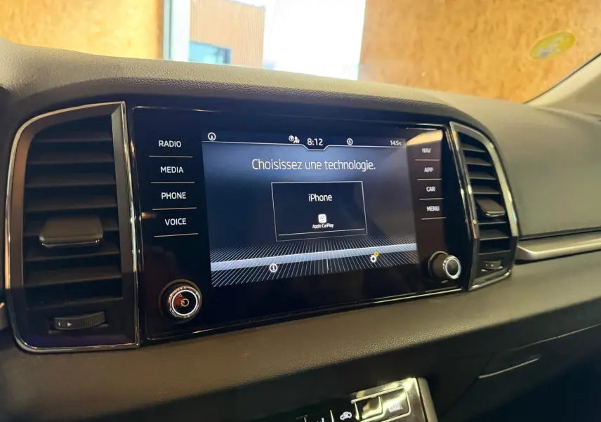 Vue rapprochée de l’écran multimédia central noir du tableau de bord du Skoda Karoq 2023 avec interface Apple CarPlay.