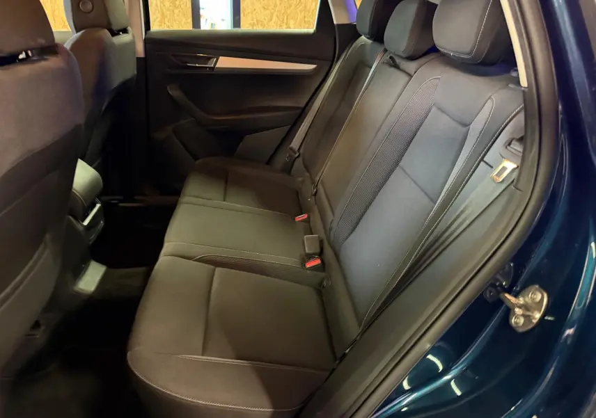 Vue intérieure côté droit sur la banquette arrière noire du Skoda Karoq bleu avec ceintures et appuie-têtes visibles.