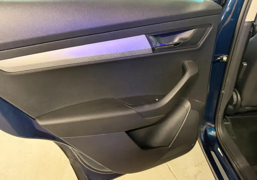 Vue rapprochée de la porte arrière droite bleu métallisé du Skoda Karoq 2023 avec garniture noire et insert décoratif gris.