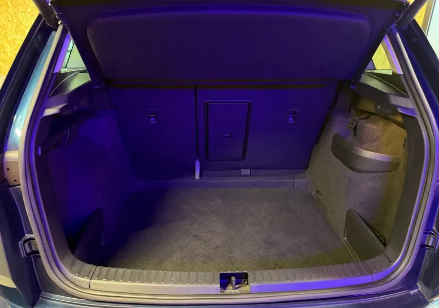 Coffre ouvert vu de l'arrière d'un Skoda Karoq bleu 2023, avec intérieur spacieux et habillage sombre.