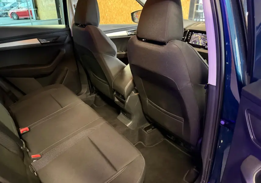Vue intérieure arrière côté droit du Skoda Karoq bleu 2023, sièges noirs et tableau de bord avec écran tactile visible.