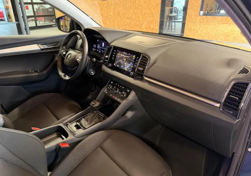 Intérieur avant droit du Skoda Karoq bleu 2023, tableau de bord noir avec écran tactile et volant multifonctions.