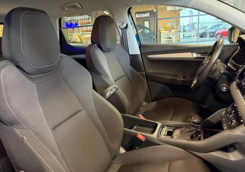 Vue intérieure côté droit du Skoda Karoq 2023, montrant les sièges avant noirs et la console centrale avec levier de vitesses automatique.