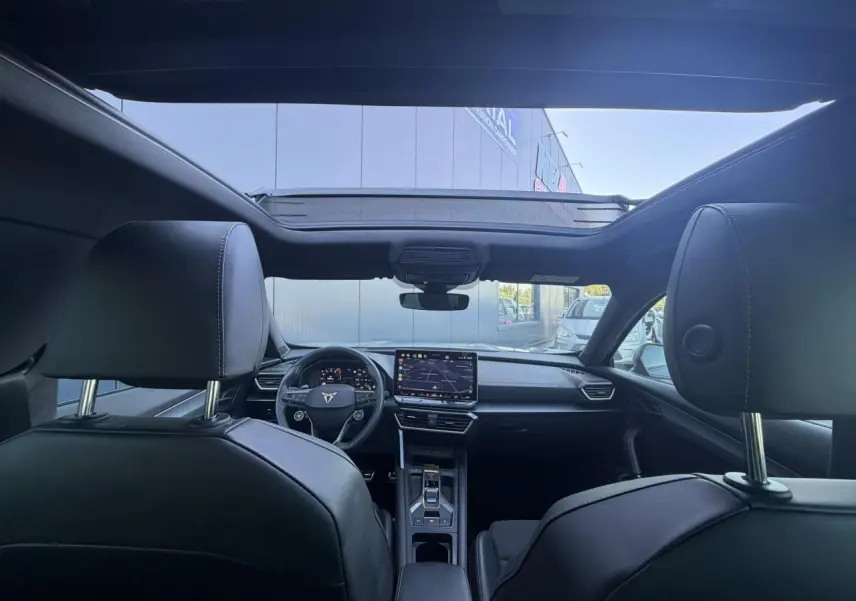 Vue intérieure avant du CUPRA Formentor 2025 gris, avec toit ouvrant panoramique et tableau de bord digital.