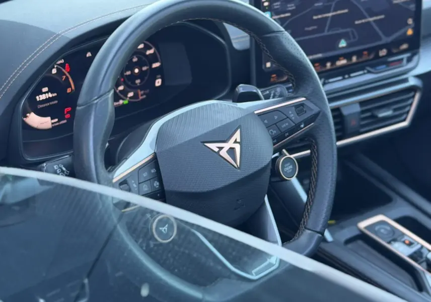 Vue rapprochée du volant cuir noir du CUPRA Formentor 2025 avec logo doré et tableau de bord numérique.