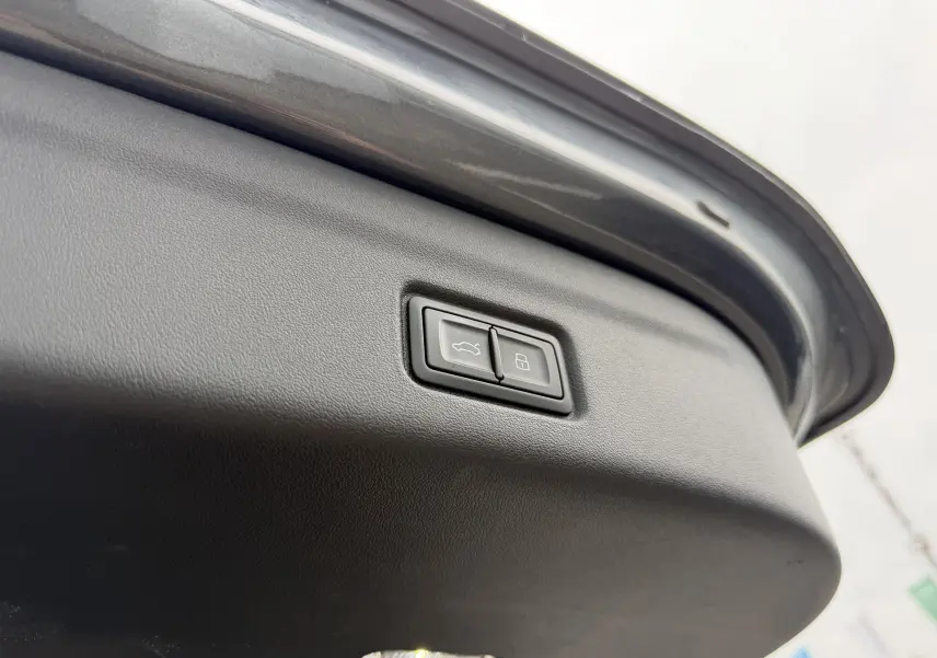 Gros plan sur le bouton de fermeture du hayon gris nacré de l'Audi Q6 e-tron 2024, vue intérieure du coffre.