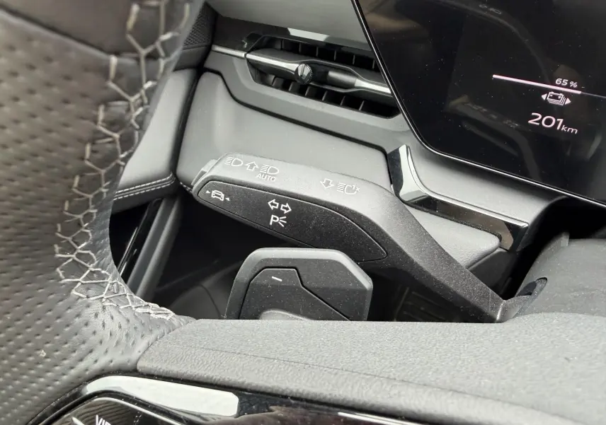 Gros plan sur la manette de clignotants et le volant perforé noir à coutures blanches de l'Audi Q6 e-tron 2024.