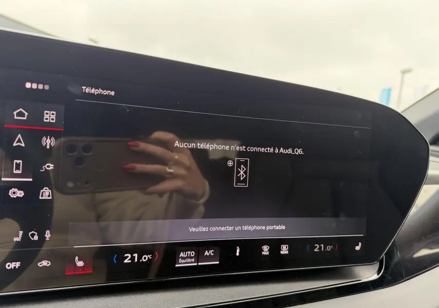 Écran tactile central de l'Audi Q6 e-tron 2024 affichant la connexion Bluetooth, avec tableau de bord noir et reflets visibles.