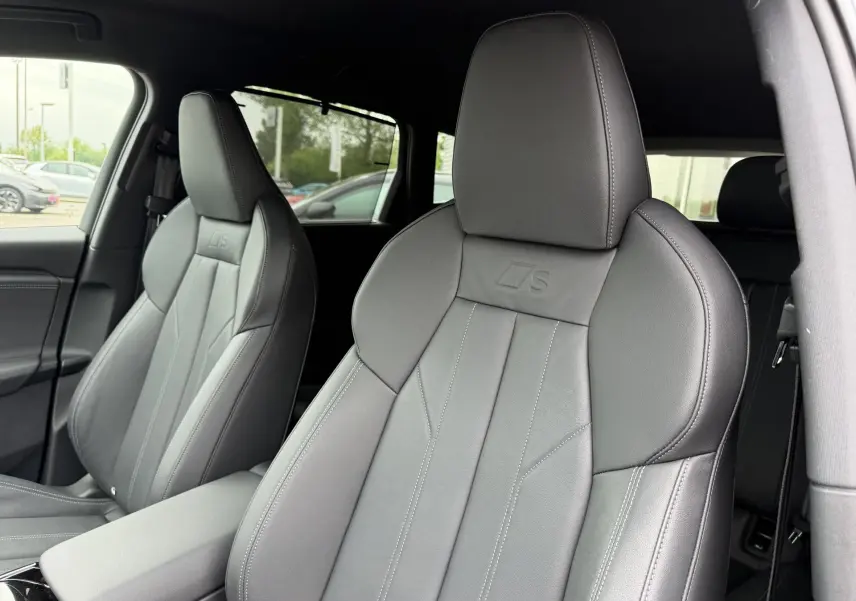 Gros plan sur les sièges avant sport gris foncé avec logo S embossé, intérieur Audi Q6 e-tron 2024.