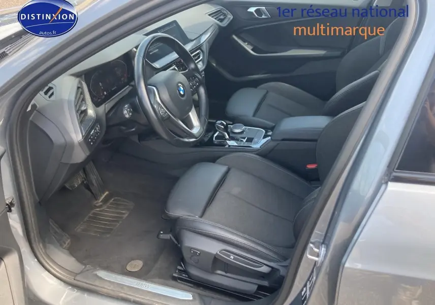 Intérieur côté conducteur d'une BMW Série 1 gris foncé, montrant sièges sport et tableau de bord moderne.