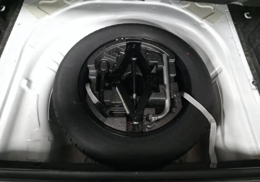 Vue plongeante sur la roue de secours et le cric dans le coffre blanc d'une Skoda Superb Combi 2018.