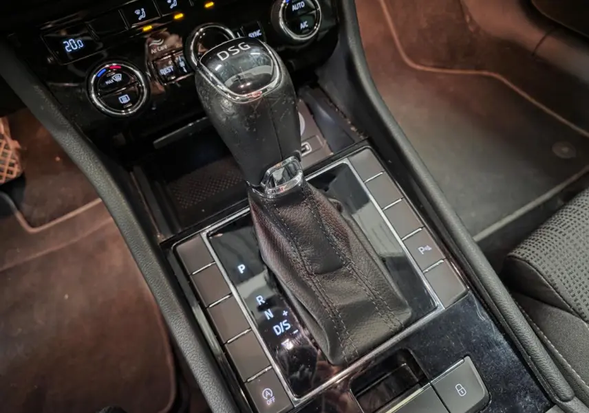 Le levier de vitesses DSG noir en cuir de la Skoda Superb Combi 2018, avec commandes et console noire brillante.