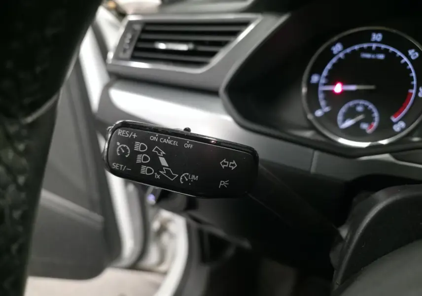 Gros plan sur la manette de commande noire du régulateur de vitesse dans l'habitacle d'une Skoda Superb Combi blanche.