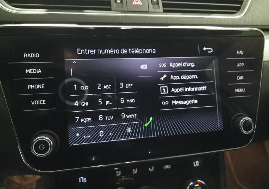 Écran tactile central du tableau de bord de la Skoda Superb Combi blanc, affichant le clavier pour entrer un numéro de téléphone.