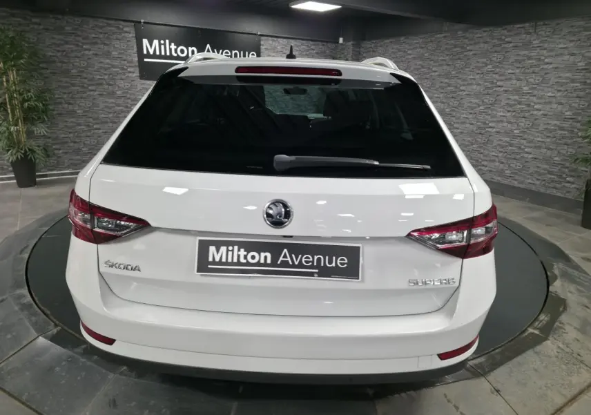 Vue arrière d'un break SKODA SUPERB blanc, avec feux arrière LED et logo ŠKODA visible sur un plateau tournant.