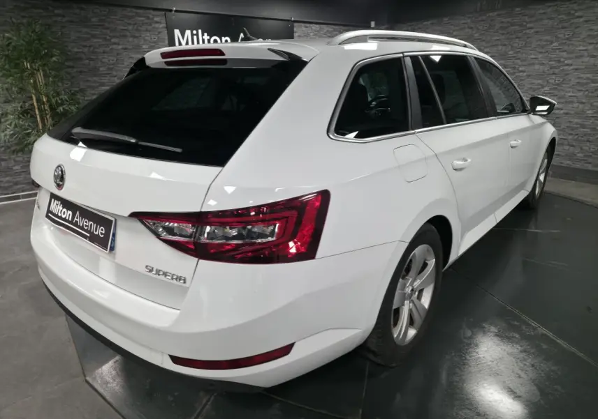 Vue 3/4 arrière droite d'un break SKODA SUPERB blanc avec feux arrière LED et jantes alliage 17 pouces.