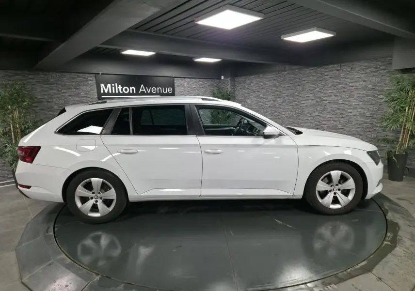 Profil droit d'un break SKODA SUPERB blanc 2018 sur plateau tournant en intérieur avec jantes alliage 5 branches.