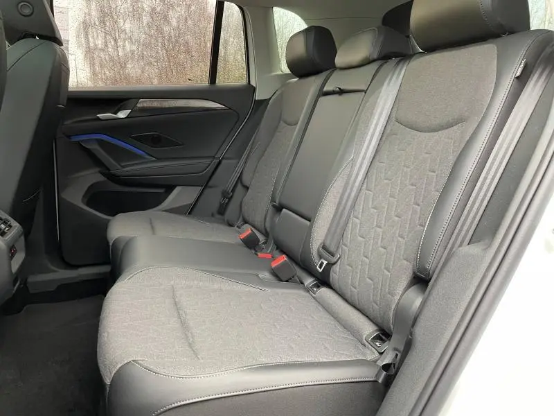 Vue côté droit de la banquette arrière en tissu anthracite du Volkswagen Tiguan blanc Pur 2025, avec ceintures et appuie-têtes.
