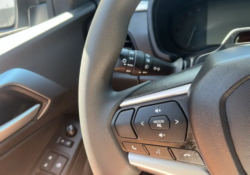 Gros plan sur le volant multifonctions côté gauche de l'Isuzu D-MAX 2026 avec commandes audio et téléphone.
