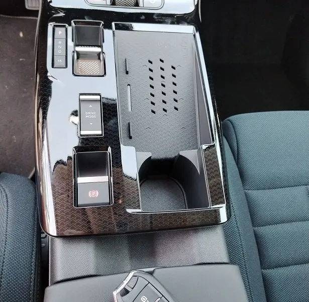 Vue rapprochée de la console centrale noire brillante du Citroën C5 Aircross 2026 avec clé posée sur l'accoudoir tissu bleu.
