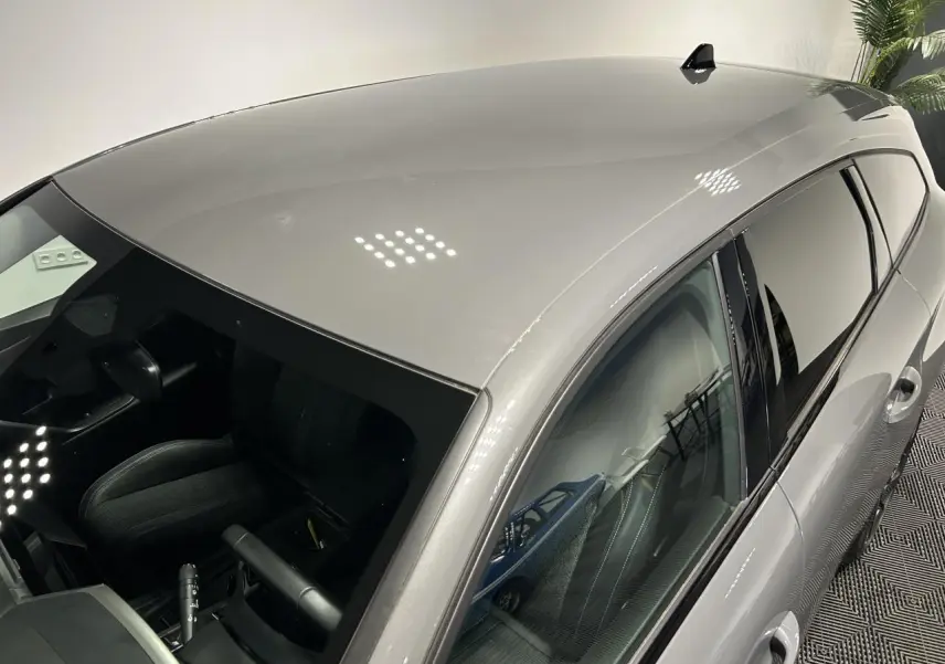 Vue plongeante côté gauche sur le break Peugeot 308 SW gris Sélénium avec vitres teintées et toit lisse.