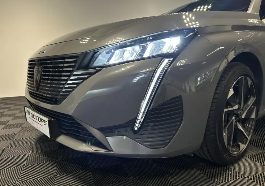 Vue 3/4 avant droit d'une Peugeot 308 SW hybride gris Sélénium avec phares LED et jantes alliage 17 pouces.