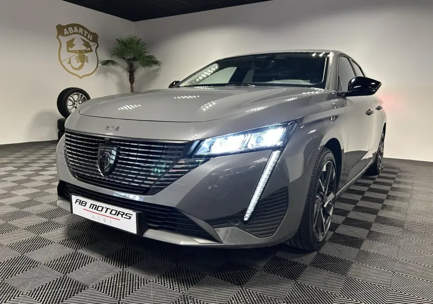 Peugeot 308 SW gris Sélénium vue 3/4 avant droit avec feux LED allumés et jantes alliage noires.
