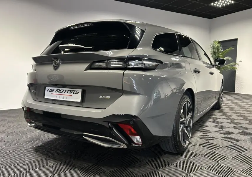 Peugeot 308 SW hybride gris Sélénium vue 3/4 arrière droit en intérieur avec jantes alliage 17 pouces.