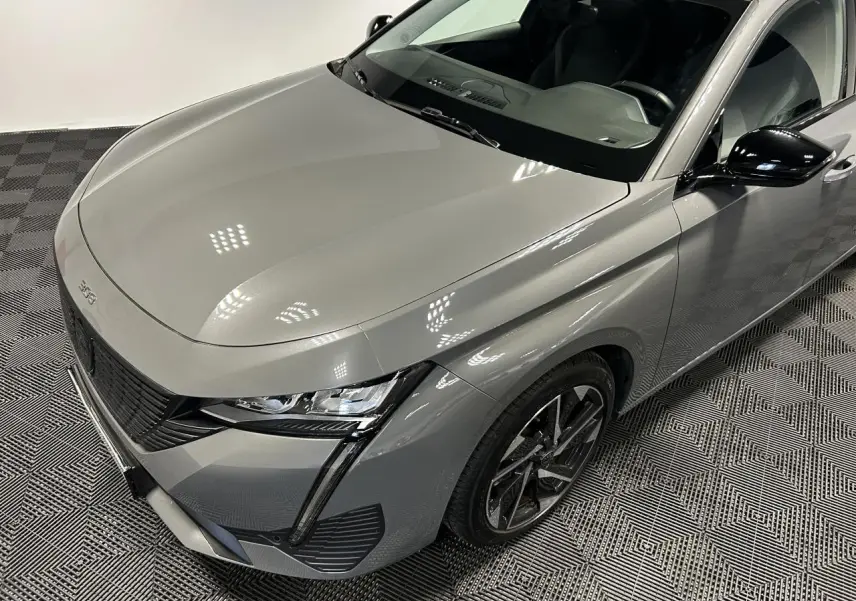 Vue 3/4 avant droit d'une Peugeot 308 SW gris Sélénium avec calandre noire et jantes alliage 17 pouces.