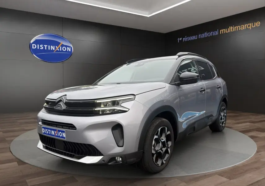 Citroën C5 Aircross hybride gris clair vue 3/4 avant droit, avec jantes distinctives et toit noir.
