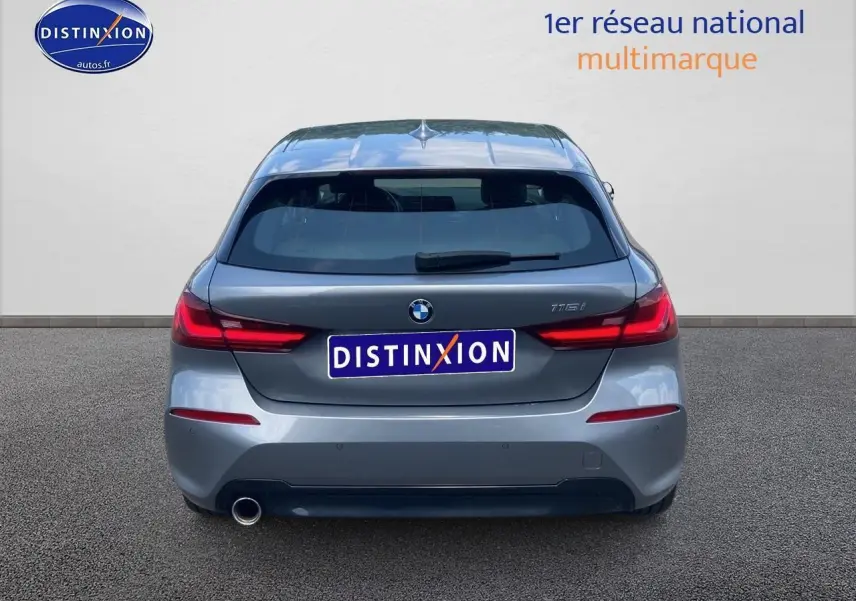 Vue arrière d'une BMW Série 1 gris foncé avec feux LED et sortie d'échappement unique côté gauche.