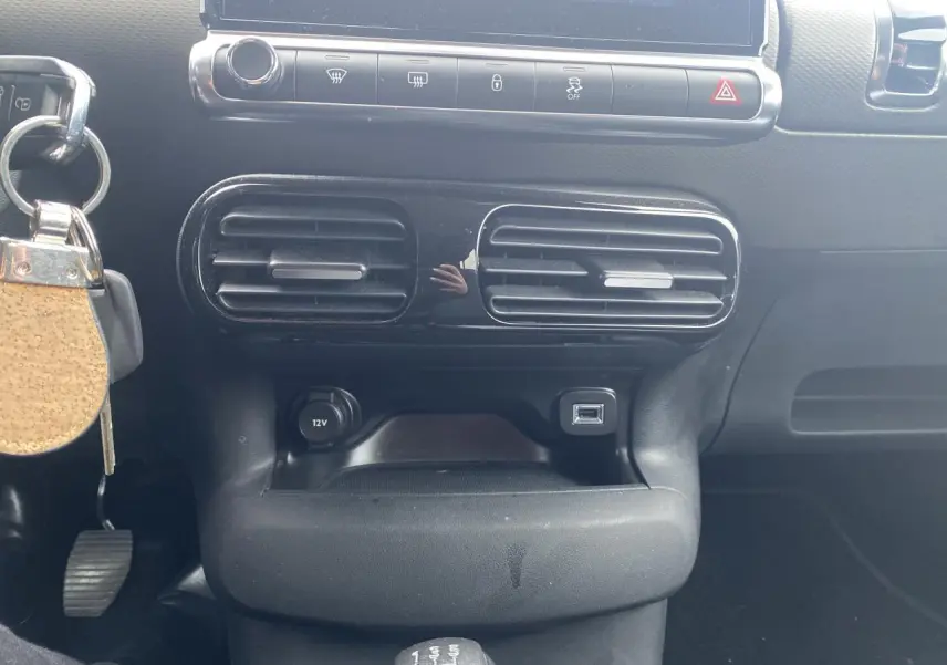 Vue rapprochée de la console centrale noire du Citroën C4 Cactus 2015 avec ventilation, prise 12V et port USB visible.